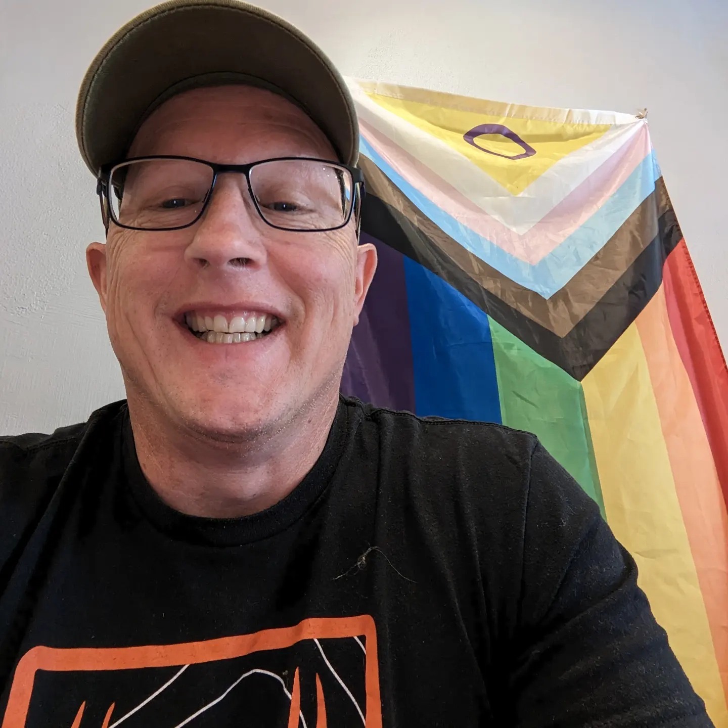 Stephen sitting in front of a Intersex Inclusive Progress Pride Flag